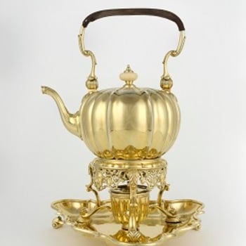A silver gilt melon-shaped tea kettle and stand, with a bail handle with leather grip, a hinged lid with ivory knop handle and a swan-neck spout; the body is engraved with stylised strapwork. The stand, fitted with a burner, has a pierced apron and three 