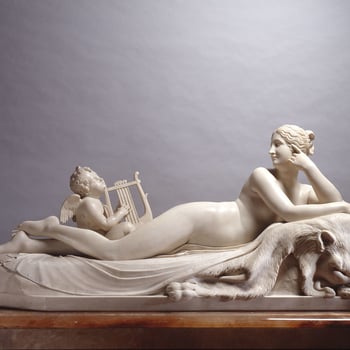 A statuary marble group of a naked nymph reclining full-length and cross-legged on a lion's pelt, beside an overturned vase from which issues a spring of water. The nymph has a head of wavy hair gathered to her right; her head is supported by her left han