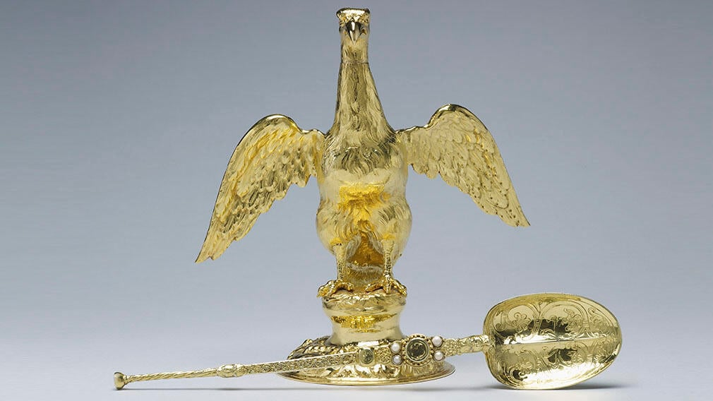 A gold flask shaped as a eagle and a large gold spoon with pearls and engraved with scroll details.