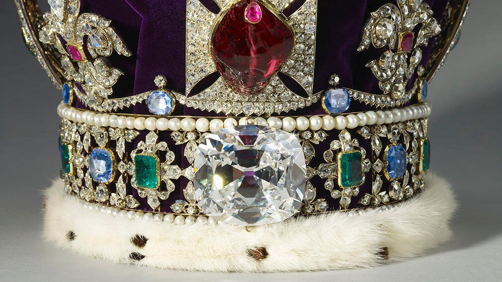 Large diamond at the base of crown surrounded with other jewels.