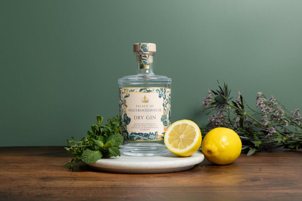 Photograph of a bottle of the Palace of Holyroodhouse Dry Gin surrounded by fresh lemons and herbs