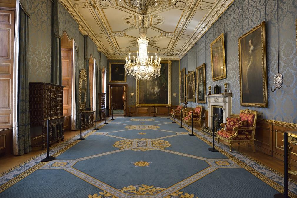 View of the Queen's Gallery with blue carpets, blue walls and grand paintings