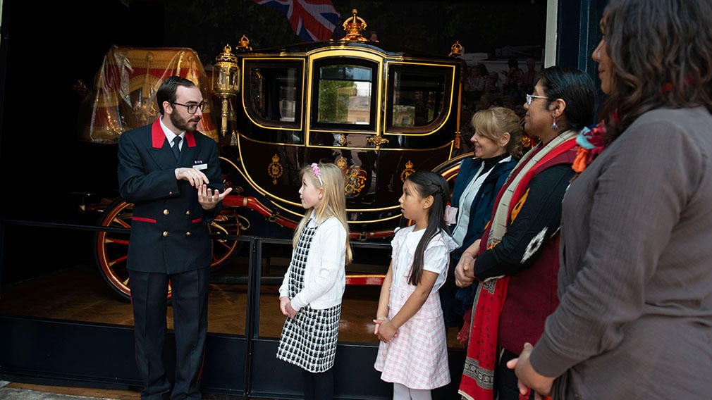 Warden talks to people in front of carriage