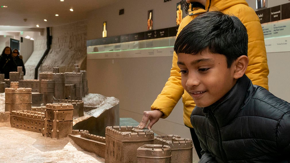 A child smiling while looking at a scale model of Windsor Castle
