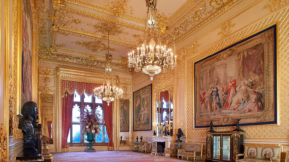 The inside of a ornate room with chandeliers and artwork on the walls
