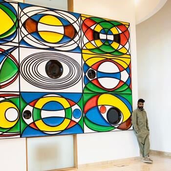 Artist Graeme Evelyn standing in front of his own abstract piece of artwork