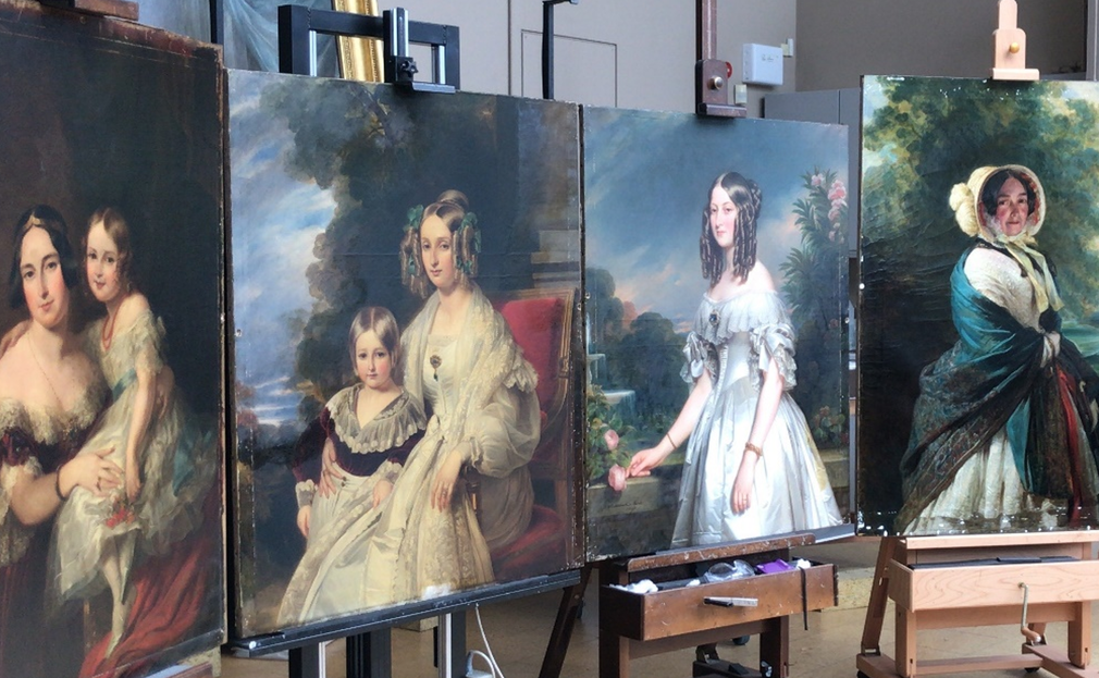 Four paintings in a conservation studio